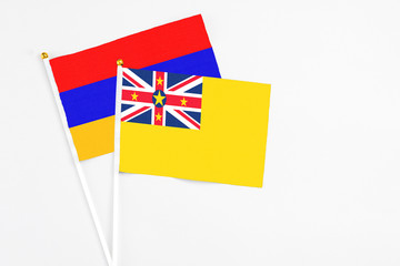 Fototapeta premium Niue and Armenia stick flags on white background. High quality fabric, miniature national flag. Peaceful global concept.White floor for copy space.