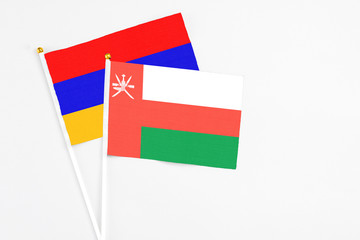 Oman and Armenia stick flags on white background. High quality fabric, miniature national flag. Peaceful global concept.White floor for copy space.