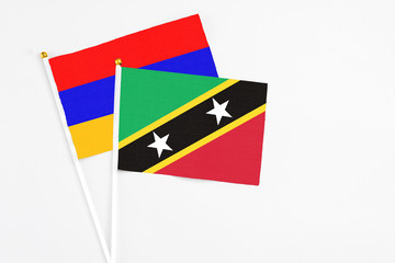 Saint Kitts And Nevis and Armenia stick flags on white background. High quality fabric, miniature national flag. Peaceful global concept.White floor for copy space.