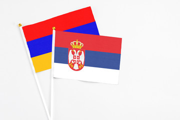 Serbia and Armenia stick flags on white background. High quality fabric, miniature national flag. Peaceful global concept.White floor for copy space.