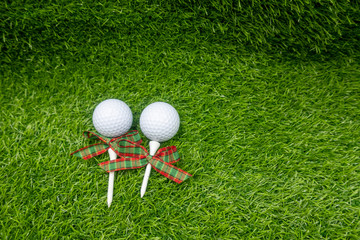 Golf ball with Christmas ribbon are on green grass
