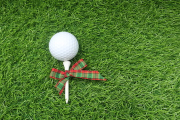Golf ball with Christmas ribbon are on green grass