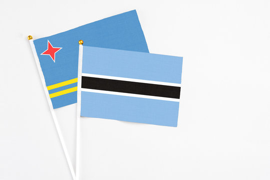 Botswana and Aruba stick flags on white background. High quality fabric, miniature national flag. Peaceful global concept.White floor for copy space.
