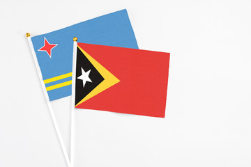 East Timor and Aruba stick flags on white background. High quality fabric, miniature national flag. Peaceful global concept.White floor for copy space.