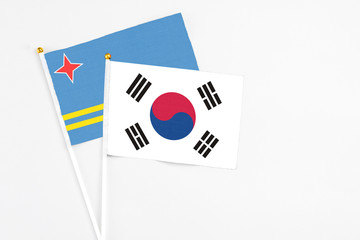 South Korea and Aruba stick flags on white background. High quality fabric, miniature national flag. Peaceful global concept.White floor for copy space.