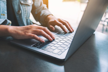 Closeup image of a woman working and typing on laptop computer on the table