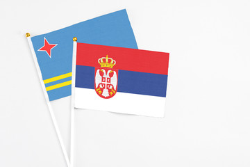 Serbia and Aruba stick flags on white background. High quality fabric, miniature national flag. Peaceful global concept.White floor for copy space.