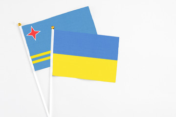 Ukraine and Aruba stick flags on white background. High quality fabric, miniature national flag. Peaceful global concept.White floor for copy space.