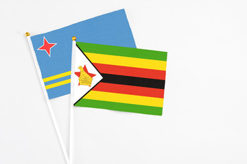 Zimbabwe and Aruba stick flags on white background. High quality fabric, miniature national flag. Peaceful global concept.White floor for copy space.