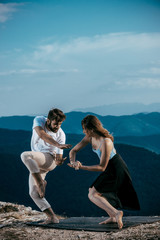 Portrait of a young dancing friends on cliff over blue sky