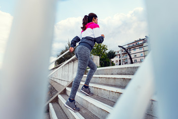 Active female runner running up stairs