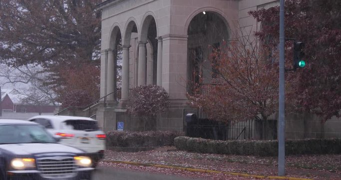 A morning snowy establishing shot of the Laughlin Memorial Public Library in Ambridge, Pennsylvania as traffic passes by. Pittsburgh suburbs.  	