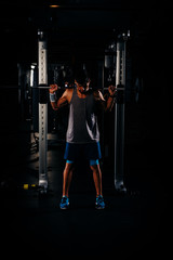 Slim muscular man working out with weights in the gym