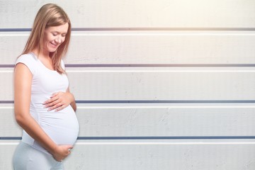 Pregnant young woman in white t shirt on wooden background
