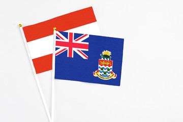 Fototapeta premium Cayman Islands and Austria stick flags on white background. High quality fabric, miniature national flag. Peaceful global concept.White floor for copy space.