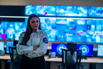 Female security guards working in surveillance room with large screens.