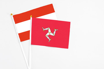 Isle Of Man and Austria stick flags on white background. High quality fabric, miniature national flag. Peaceful global concept.White floor for copy space.