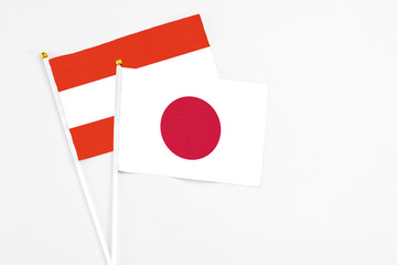 Japan and Austria stick flags on white background. High quality fabric, miniature national flag. Peaceful global concept.White floor for copy space.