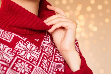 young woman wearing red and white hight neck christmas sweater with christmas lights as a background