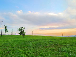 two silhouettes of people walking in the distance on a glade in the Park against the sunset