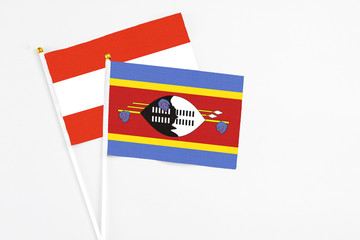 Swaziland and Austria stick flags on white background. High quality fabric, miniature national flag. Peaceful global concept.White floor for copy space.