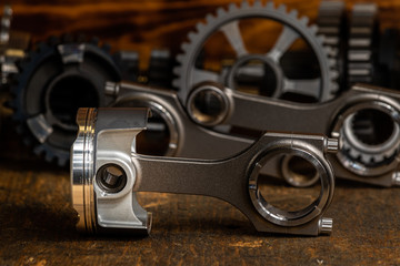 high performance racing motorcycle piston and Conrods on a workbench with gears in the background. 