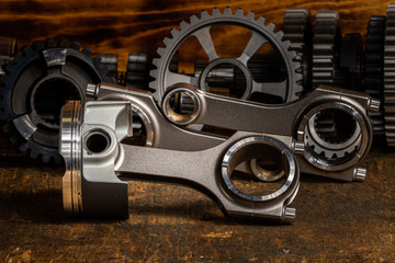 high performance racing motorcycle piston and Conrods on a workbench with gears in the background. 