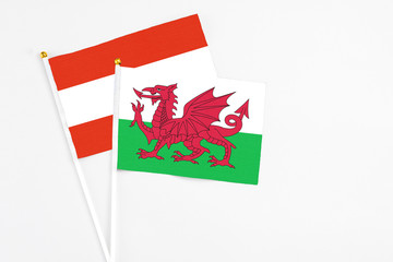 Wales and Austria stick flags on white background. High quality fabric, miniature national flag. Peaceful global concept.White floor for copy space.