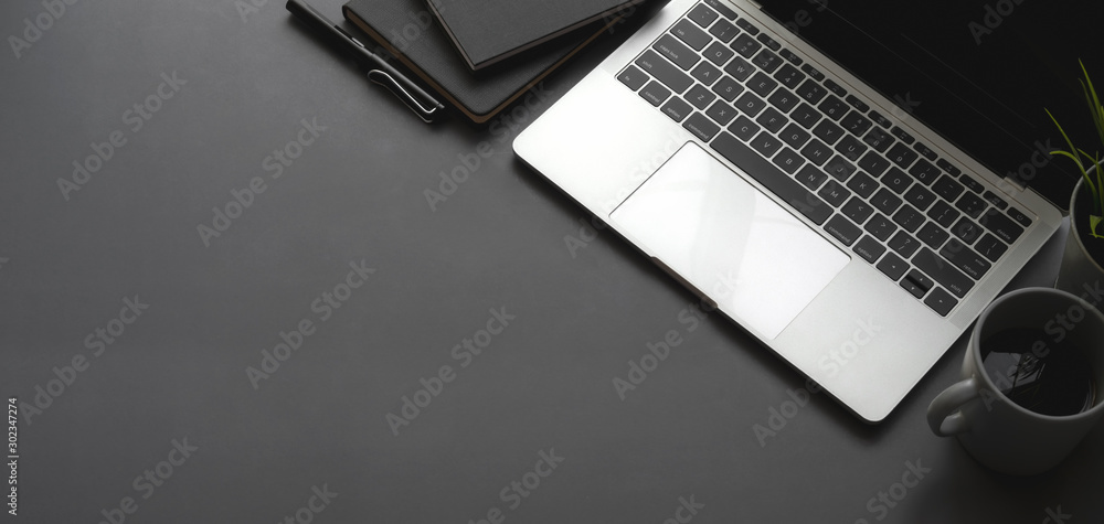 Poster overhead shot of dark stylish workspace with laptop computer black notebook on black table