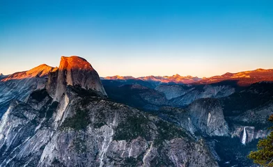 Fototapeten Panoramablick auf das Sonnenlicht, das die Berggipfel des Half Dome und des Yosemite Valley bei Sonnenuntergang im Yosemite National Park beleuchtet © mitgirl