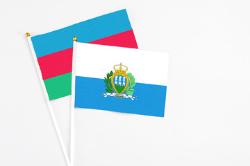 San Marino and Azerbaijan stick flags on white background. High quality fabric, miniature national flag. Peaceful global concept.White floor for copy space.