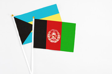 Afghanistan and Bahamas stick flags on white background. High quality fabric, miniature national flag. Peaceful global concept.White floor for copy space.
