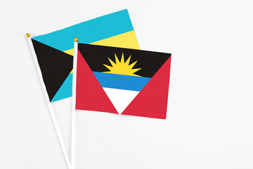 Antigua and Barbuda and Bahamas stick flags on white background. High quality fabric, miniature national flag. Peaceful global concept.White floor for copy space.