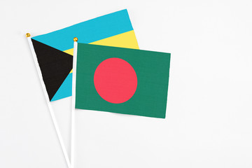 Bangladesh and Bahamas stick flags on white background. High quality fabric, miniature national flag. Peaceful global concept.White floor for copy space.