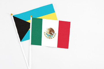 Mexico and Bahamas stick flags on white background. High quality fabric, miniature national flag. Peaceful global concept.White floor for copy space.