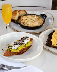 Haute cuisine - grilled sandwich with avocado guacamole sauce and two sunny side up eggs outside restaurant in a sunny day