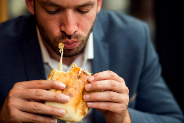 Businessman eating junk food sandwich 