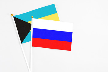 Russia and Bahamas stick flags on white background. High quality fabric, miniature national flag. Peaceful global concept.White floor for copy space.