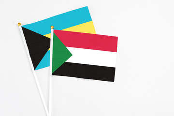 Sudan and Bahamas stick flags on white background. High quality fabric, miniature national flag. Peaceful global concept.White floor for copy space.