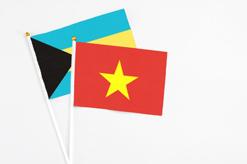 Vietnam and Bahamas stick flags on white background. High quality fabric, miniature national flag. Peaceful global concept.White floor for copy space.