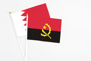 Angola and Bahrain stick flags on white background. High quality fabric, miniature national flag. Peaceful global concept.White floor for copy space.