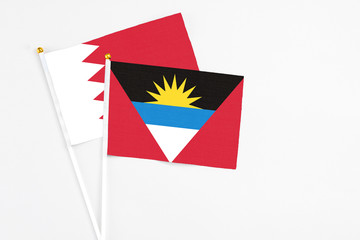 Antigua and Barbuda and Bahrain stick flags on white background. High quality fabric, miniature national flag. Peaceful global concept.White floor for copy space.