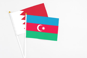 Azerbaijan and Bahrain stick flags on white background. High quality fabric, miniature national flag. Peaceful global concept.White floor for copy space.
