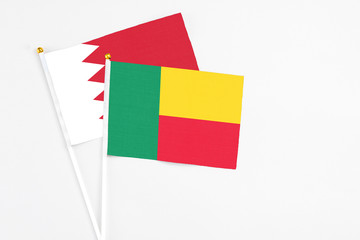 Benin and Bahrain stick flags on white background. High quality fabric, miniature national flag. Peaceful global concept.White floor for copy space.