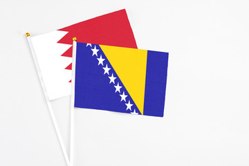 Bosnia Herzegovina and Bahrain stick flags on white background. High quality fabric, miniature national flag. Peaceful global concept.White floor for copy space.