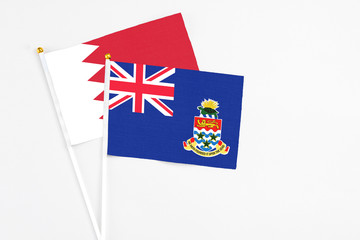 Cayman Islands and Bahrain stick flags on white background. High quality fabric, miniature national...
