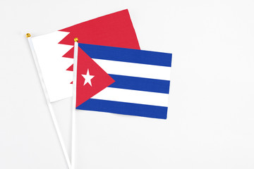 Cuba and Bahrain stick flags on white background. High quality fabric, miniature national flag. Peaceful global concept.White floor for copy space.