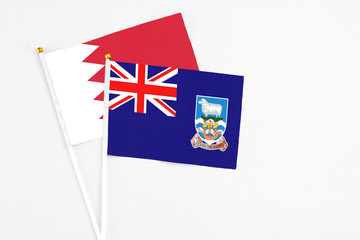 Falkland Islands and Bahrain stick flags on white background. High quality fabric, miniature national flag. Peaceful global concept.White floor for copy space.