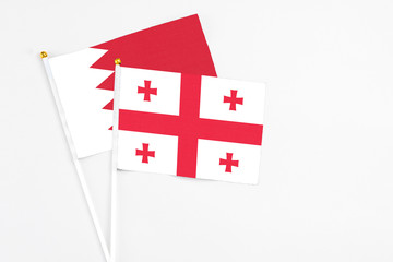 Georgia and Bahrain stick flags on white background. High quality fabric, miniature national flag. Peaceful global concept.White floor for copy space.