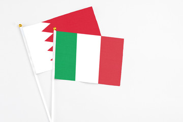 Italy and Bahrain stick flags on white background. High quality fabric, miniature national flag. Peaceful global concept.White floor for copy space.